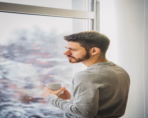 A person taking a calm break near a window looking at the city